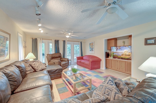 living room with light hardwood / wood-style floors, ceiling fan, a textured ceiling, and track lighting