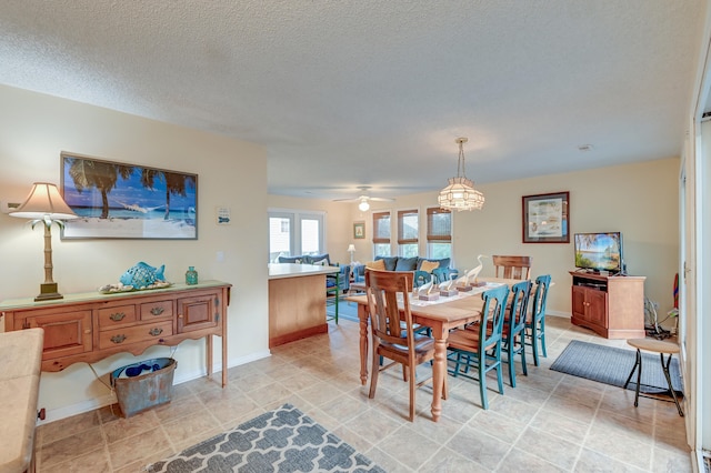 dining area featuring a textured ceiling, light tile patterned flooring, and ceiling fan with notable chandelier