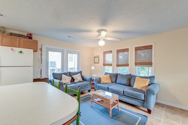 living room featuring ceiling fan and a textured ceiling