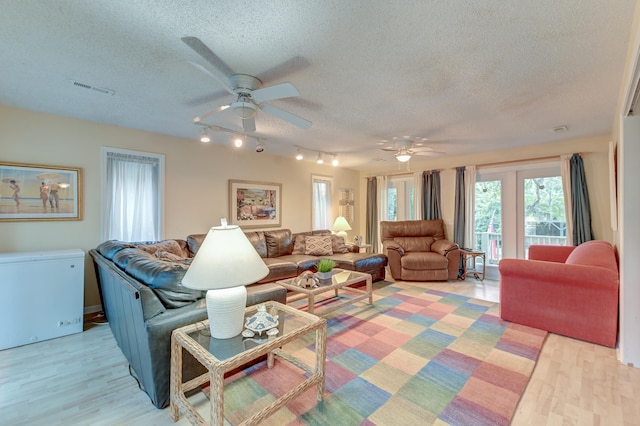 living room featuring light hardwood / wood-style floors, a textured ceiling, and ceiling fan