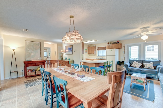 tiled dining area with sink, a textured ceiling, and ceiling fan