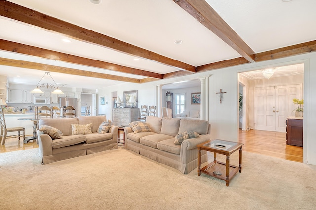 living area featuring light carpet, a notable chandelier, decorative columns, and beamed ceiling