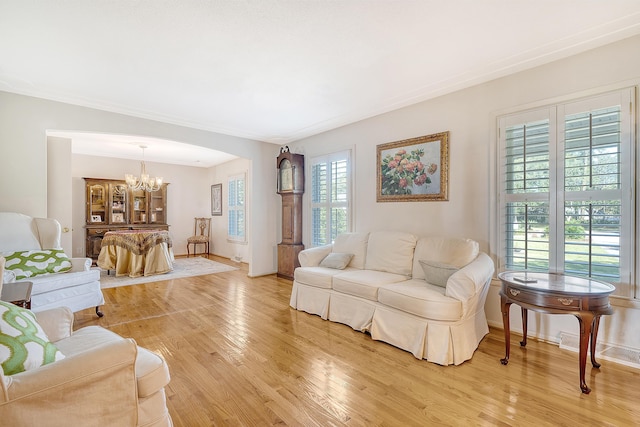 living room with light wood-style floors, arched walkways, a notable chandelier, and baseboards