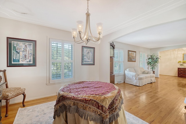 bedroom with arched walkways, multiple windows, and light wood-type flooring