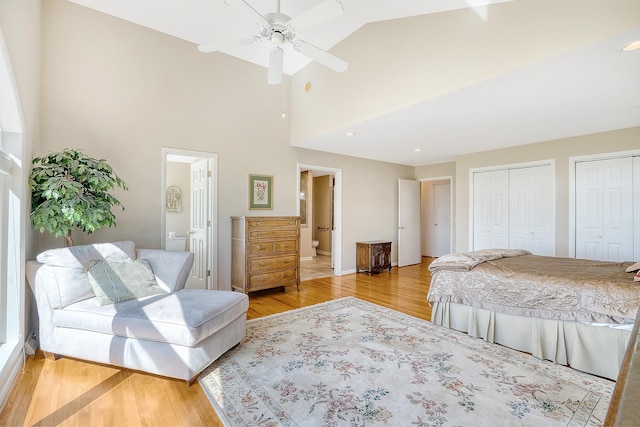 bedroom with ensuite bath, high vaulted ceiling, two closets, and wood finished floors