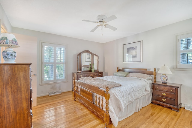 bedroom with light wood finished floors, visible vents, and baseboards