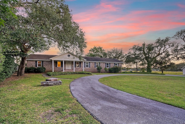 view of front facade with brick siding, curved driveway, and a front lawn