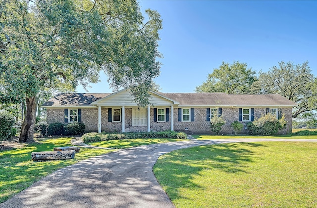 ranch-style home with aphalt driveway, covered porch, brick siding, crawl space, and a front lawn