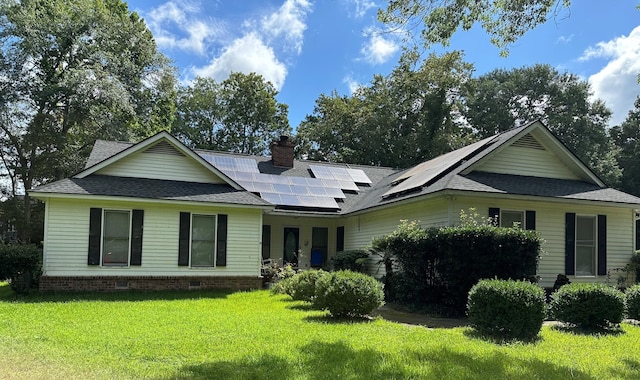 view of front facade featuring solar panels and a front yard