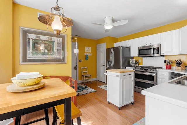 kitchen with butcher block countertops, a ceiling fan, white cabinetry, stainless steel appliances, and light wood-style flooring