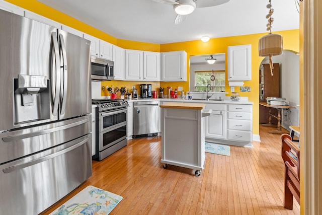 kitchen with a ceiling fan, light wood-style floors, white cabinetry, a sink, and stainless steel appliances