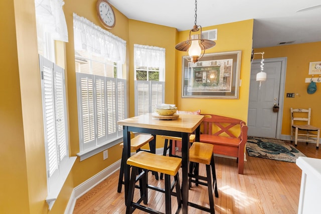 dining room with baseboards, light wood finished floors, and visible vents