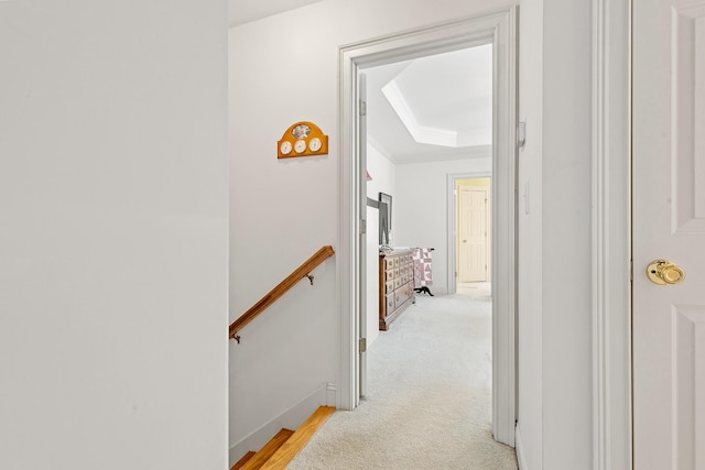corridor with crown molding, baseboards, an upstairs landing, and a tray ceiling