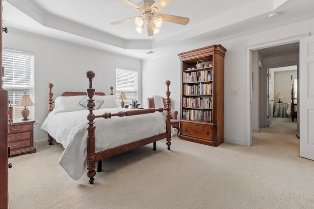 bedroom featuring crown molding, a tray ceiling, light colored carpet, and attic access