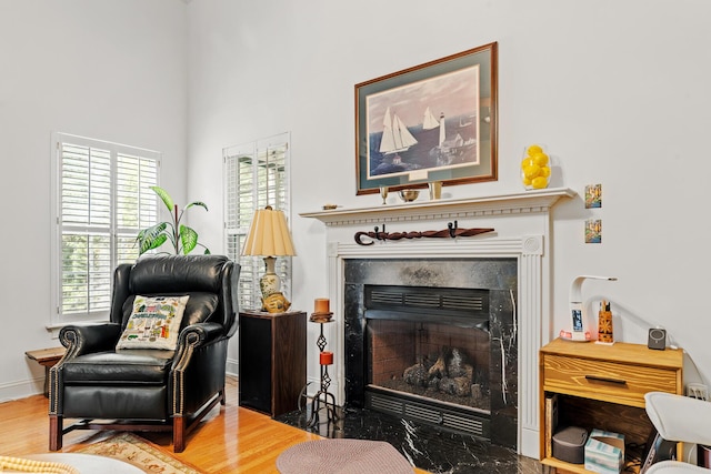 sitting room featuring a premium fireplace, baseboards, and wood finished floors