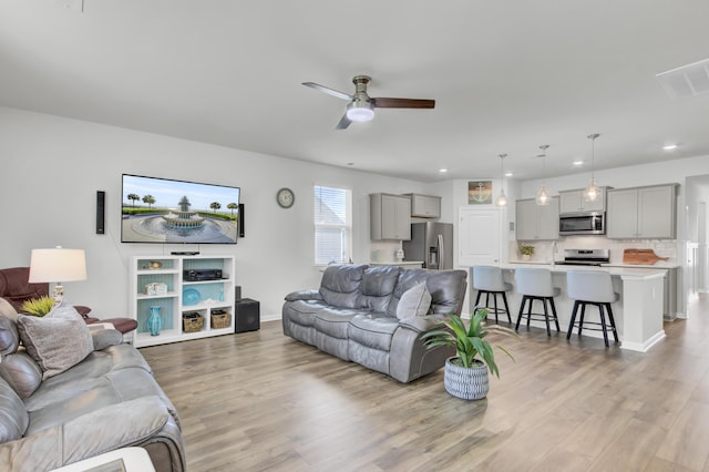 living room featuring ceiling fan and light hardwood / wood-style floors