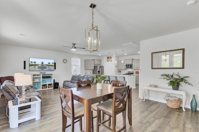 dining room with light hardwood / wood-style flooring and ceiling fan with notable chandelier