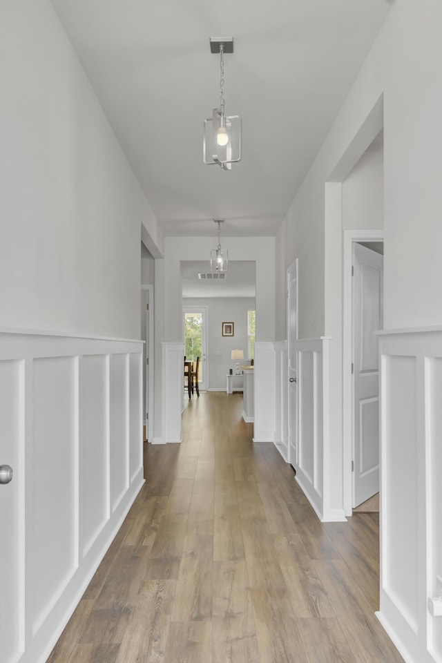 hallway with a notable chandelier and light hardwood / wood-style flooring