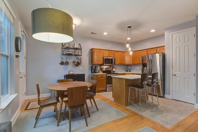 5134 E Liberty Park Cir N, Charleston, SC 29405 - kitchen featuring appliances with stainless steel finishes, a center island, light countertops, brown cabinetry, and light wood-type flooring