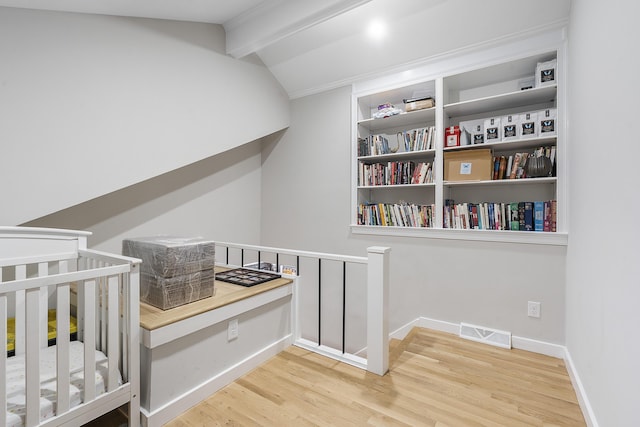 bedroom featuring lofted ceiling with beams, wood finished floors, visible vents, and baseboards