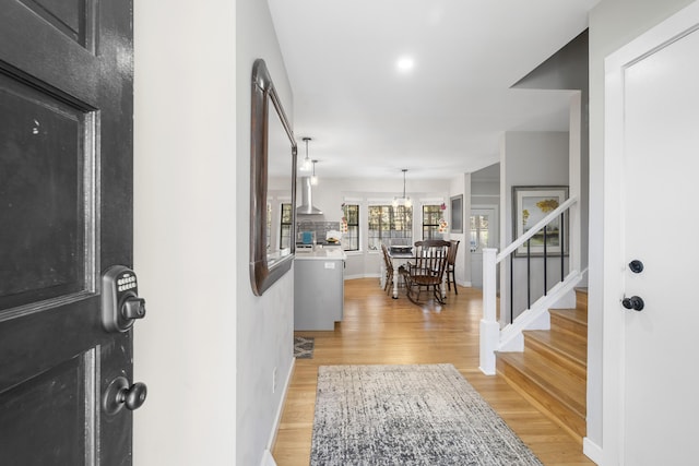 entryway with light wood-type flooring, baseboards, and stairway