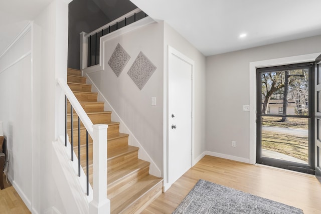 foyer entrance featuring stairs, light wood-style flooring, and baseboards