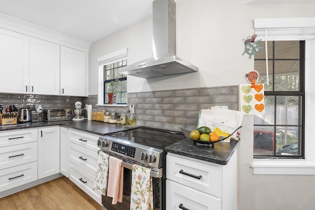 kitchen featuring backsplash, light wood-style flooring, exhaust hood, electric range, and white cabinets