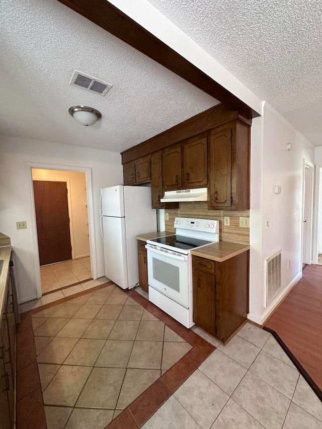 kitchen featuring tasteful backsplash, dark brown cabinets, a textured ceiling, light wood-type flooring, and white appliances