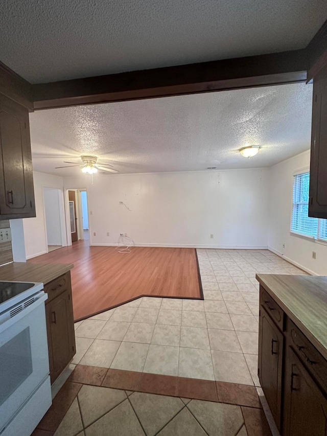 kitchen featuring ceiling fan, white electric stove, light tile floors, a textured ceiling, and dark brown cabinets