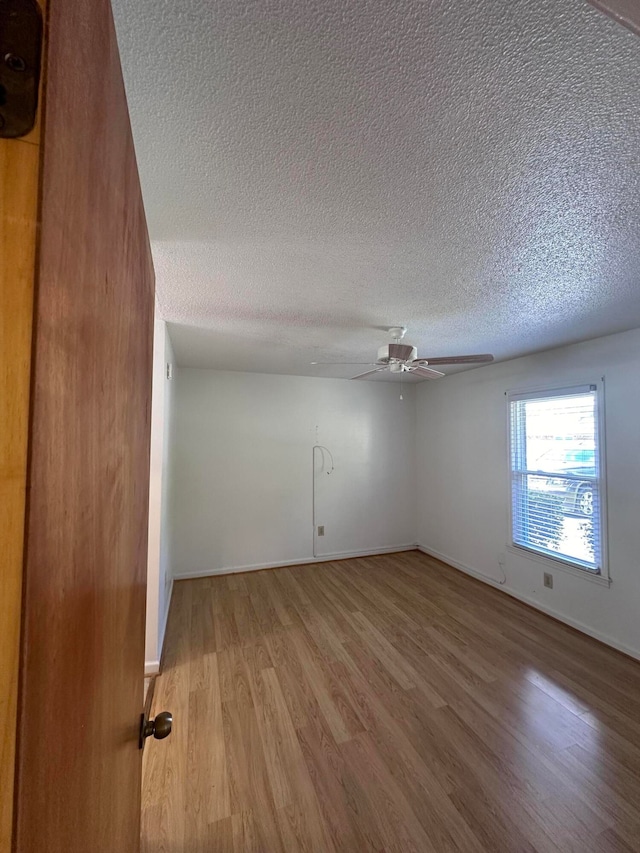 empty room featuring ceiling fan, hardwood / wood-style floors, and a textured ceiling