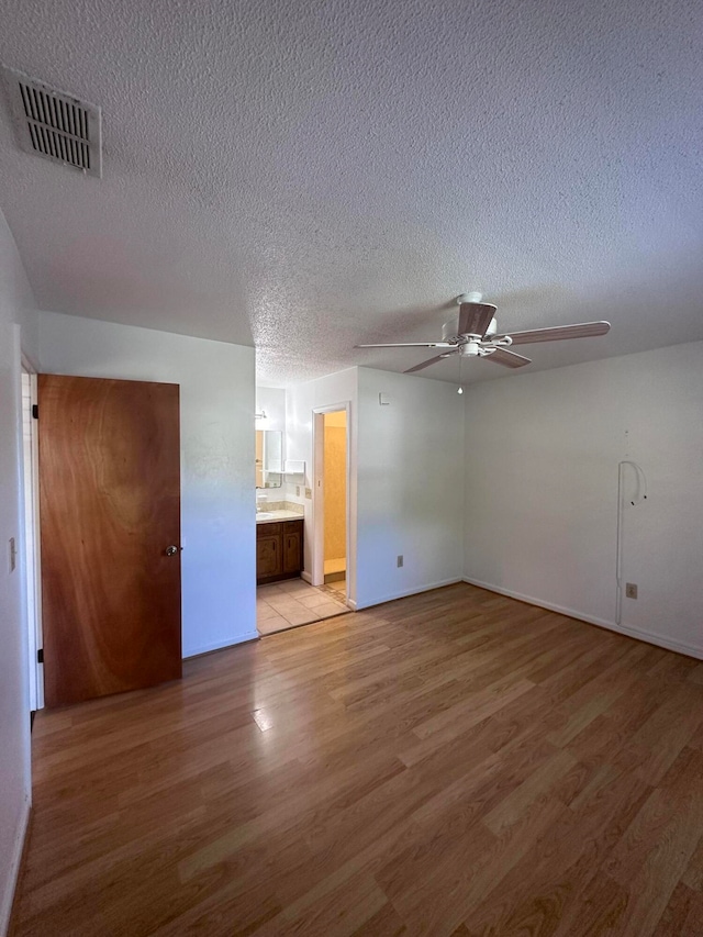 interior space with light tile flooring, ceiling fan, connected bathroom, and a textured ceiling