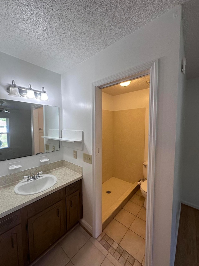 bathroom with toilet, oversized vanity, a textured ceiling, walk in shower, and tile floors