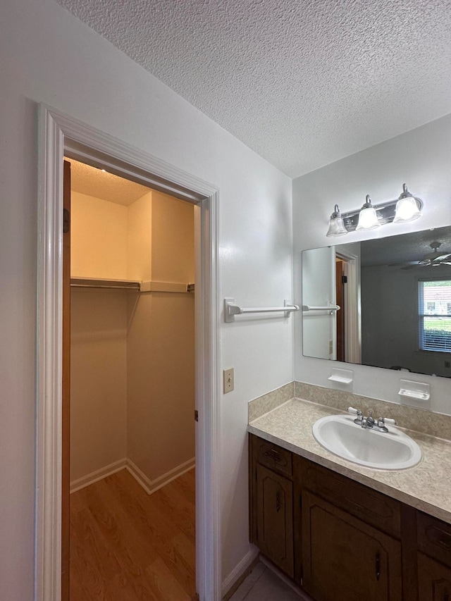 bathroom featuring ceiling fan, a textured ceiling, vanity, and wood-type flooring