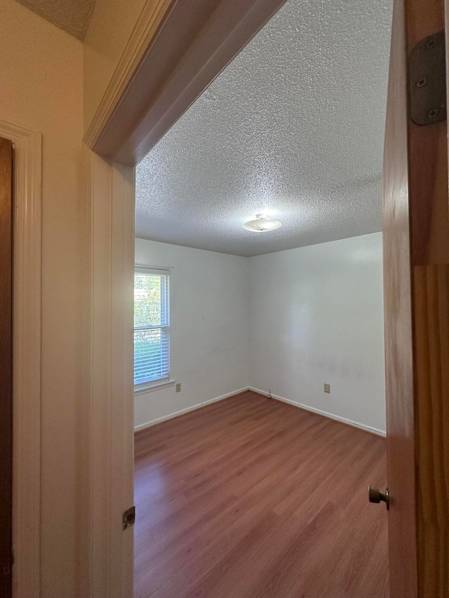 unfurnished room featuring a textured ceiling and dark hardwood / wood-style floors