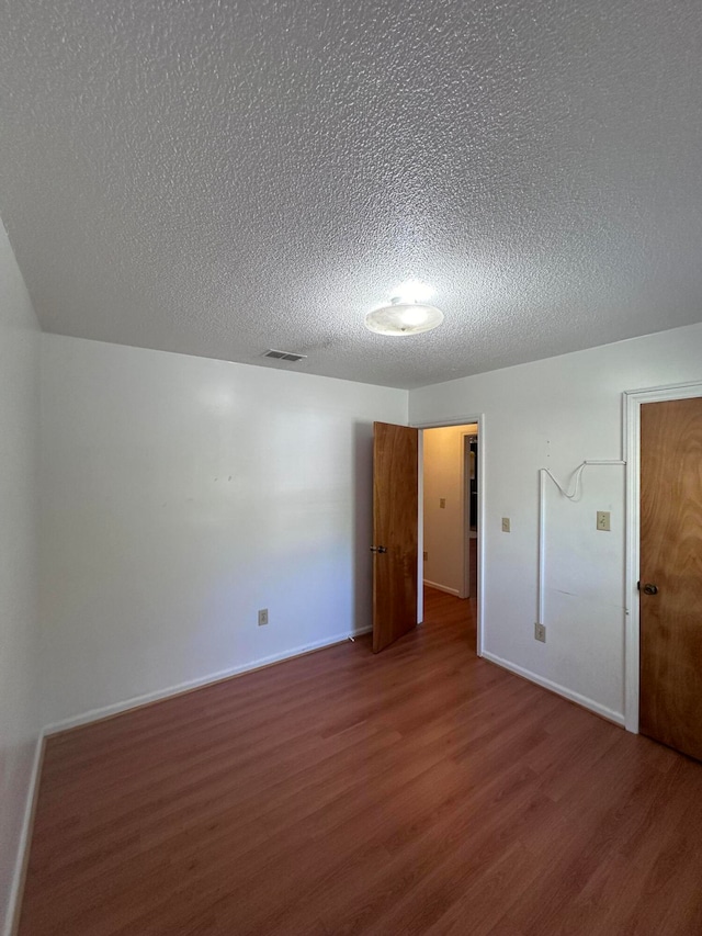 spare room with dark hardwood / wood-style floors and a textured ceiling