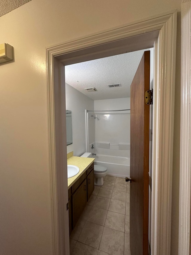 full bathroom with toilet, washtub / shower combination, tile floors, a textured ceiling, and vanity