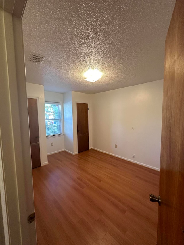 spare room featuring a textured ceiling and dark hardwood / wood-style flooring