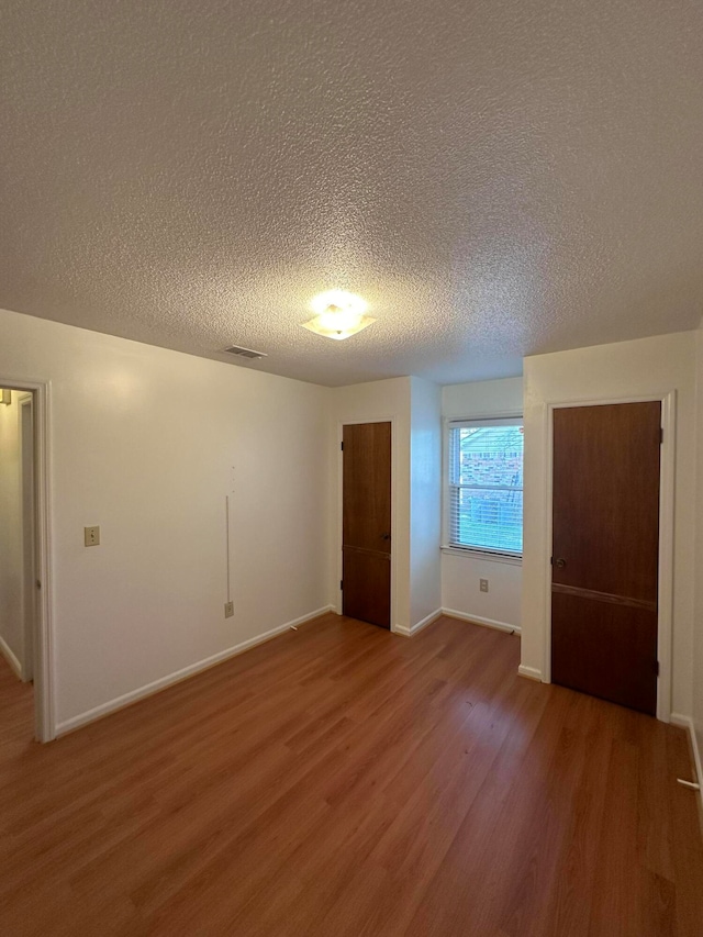 spare room with a textured ceiling and dark hardwood / wood-style floors