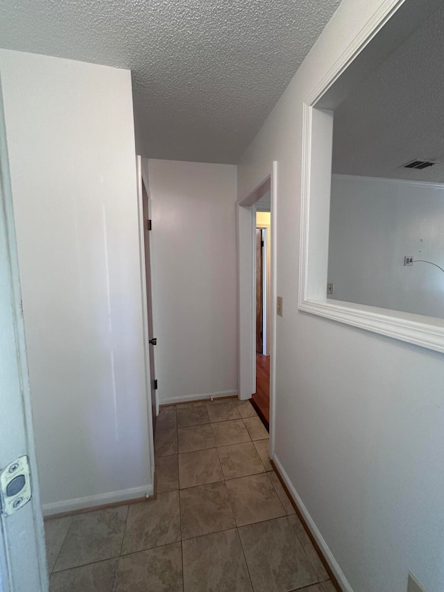 hallway featuring a textured ceiling and light tile flooring