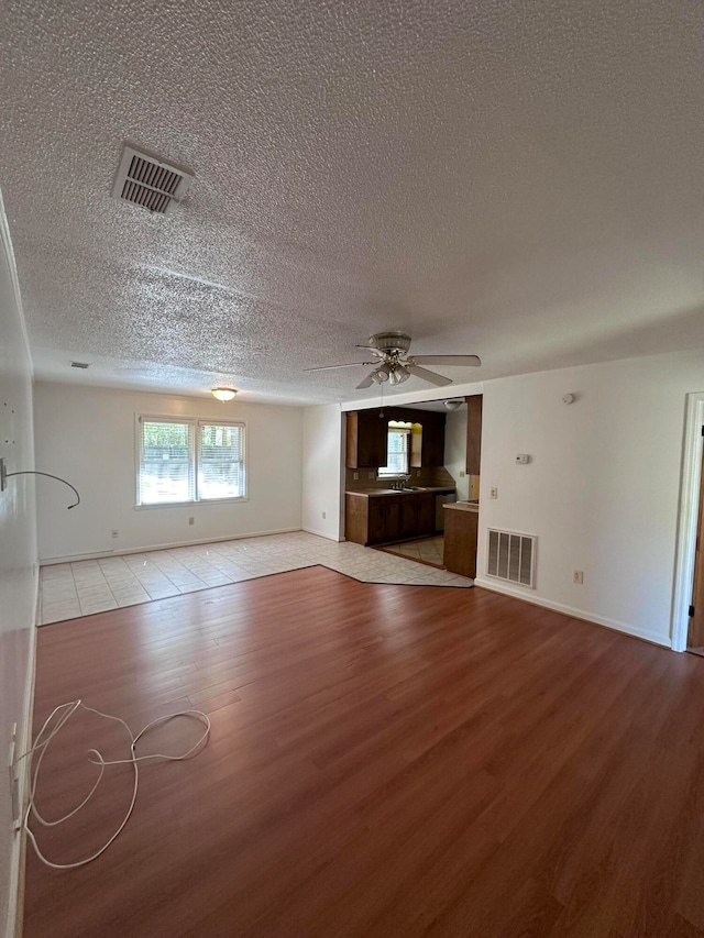 interior space with a textured ceiling, ceiling fan, and light tile floors