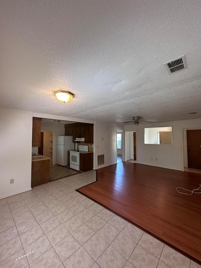 tiled empty room with ceiling fan and a textured ceiling