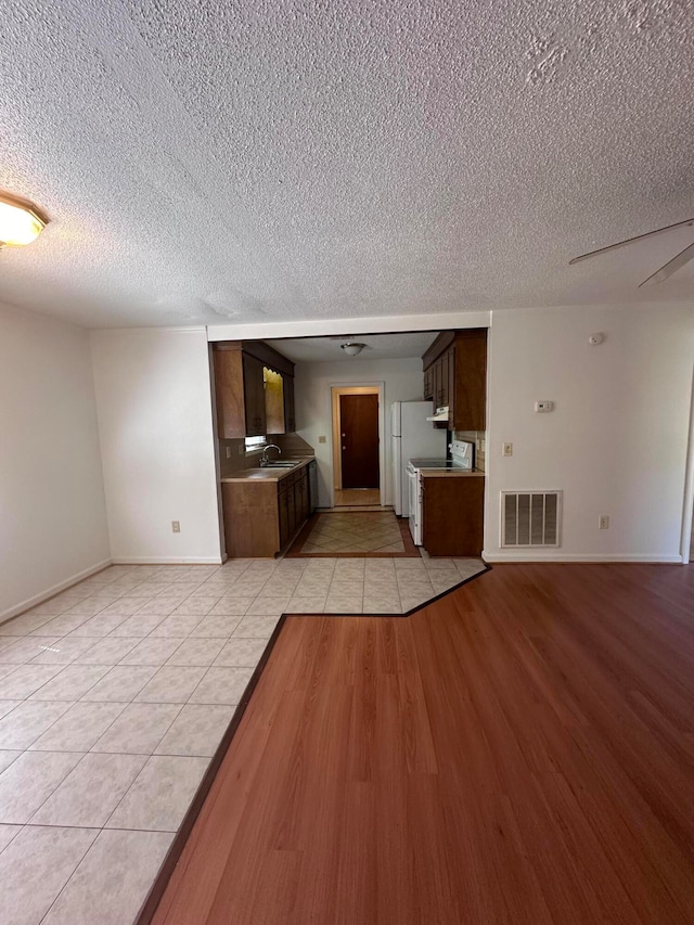 unfurnished room featuring a textured ceiling, sink, and light tile floors