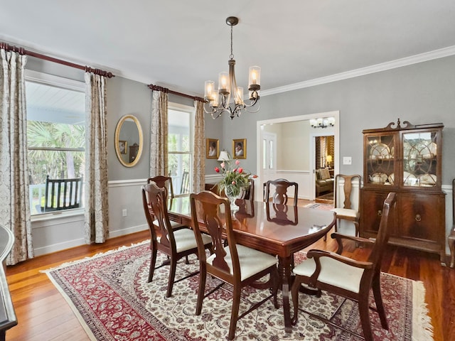 dining space featuring wood-type flooring, crown molding, and a chandelier