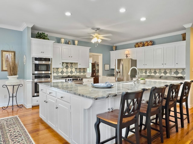 kitchen featuring white cabinetry, light hardwood / wood-style flooring, stainless steel appliances, and a large island