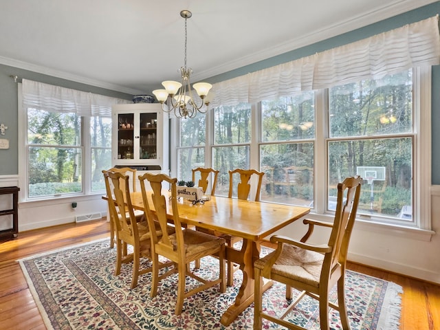 dining space featuring wood-type flooring, crown molding, and a chandelier