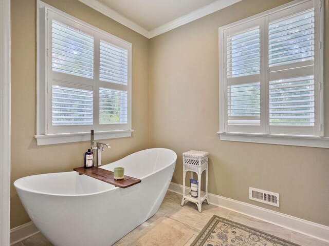 bathroom with a tub, tile patterned floors, ornamental molding, and a healthy amount of sunlight