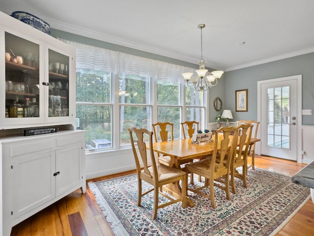 dining area with crown molding, light hardwood / wood-style floors, and a notable chandelier