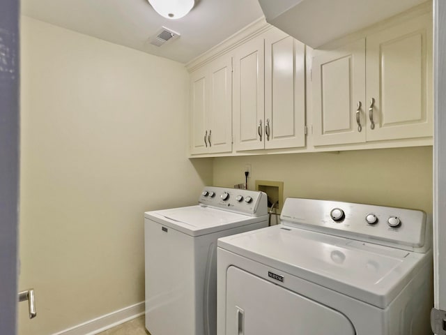 clothes washing area featuring independent washer and dryer and cabinets