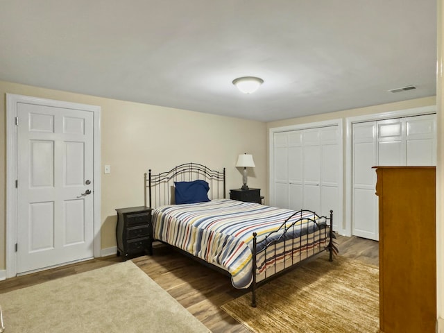 bedroom with two closets and hardwood / wood-style flooring