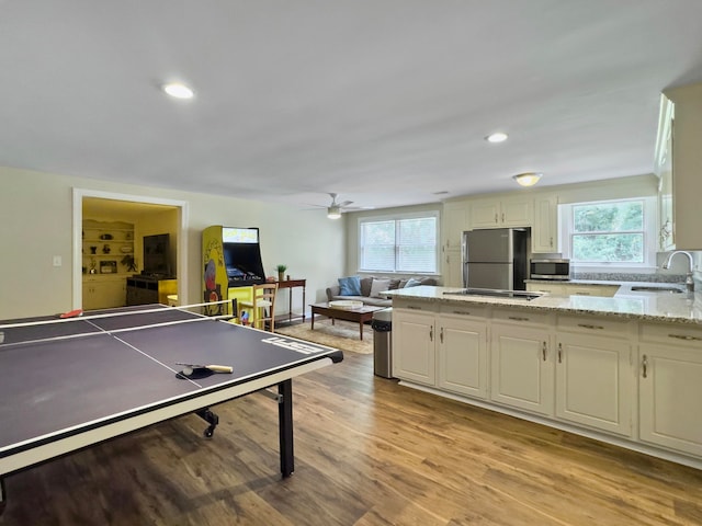 game room with ceiling fan, a wealth of natural light, sink, and light hardwood / wood-style flooring